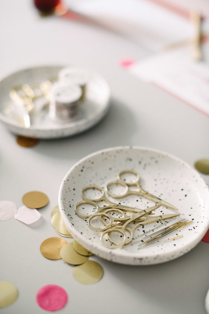 Teller mit kleinen, goldenen Scheren